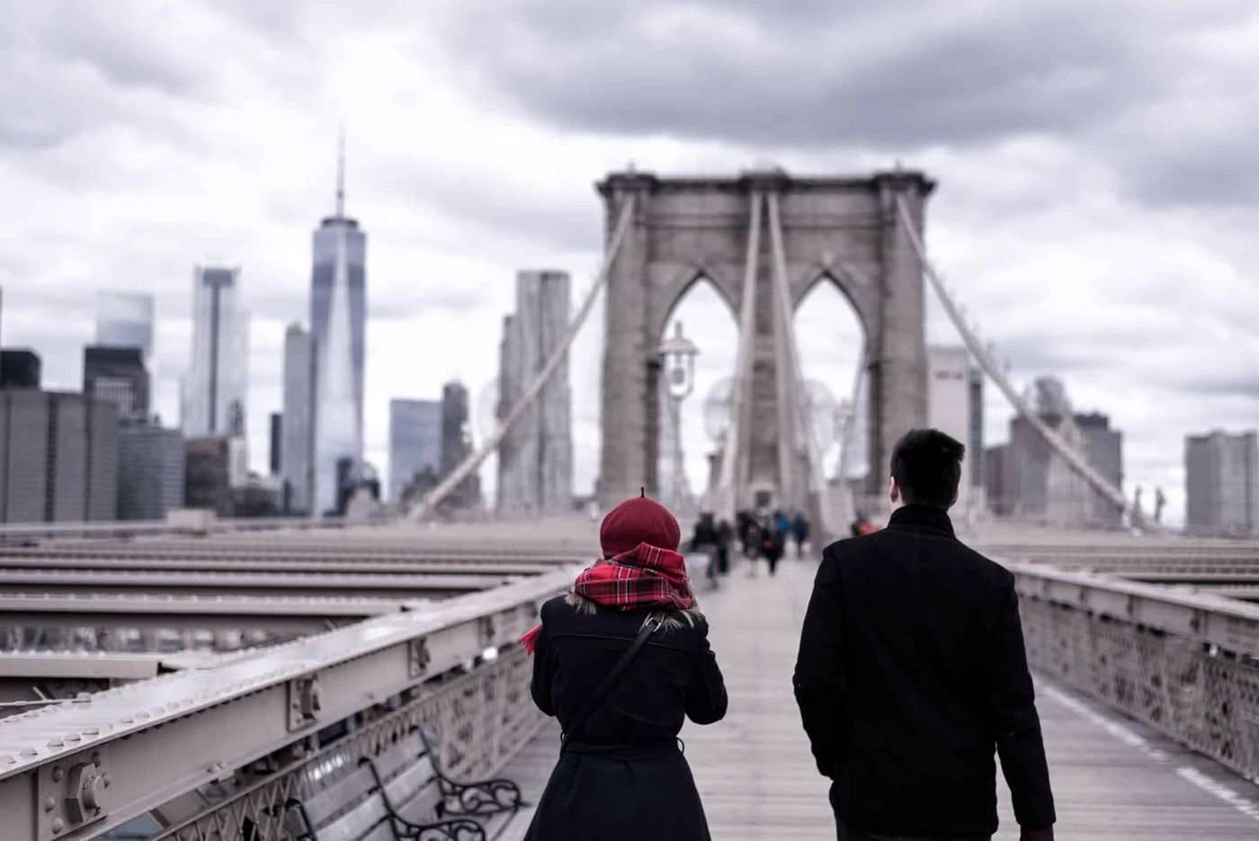 Two people walking across the Brooklyn Bridge toward Manhattan